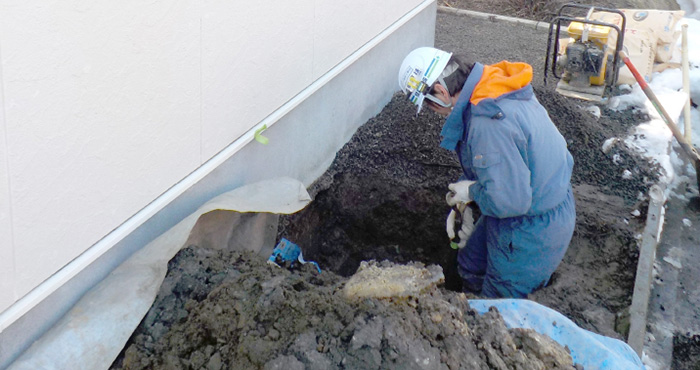 地面に穴を掘って工事をしている男性作業員