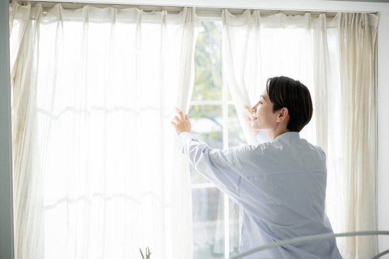 カーテンを開く女性