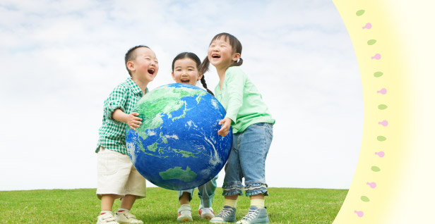 大きい地球儀を持った笑顔の3人の子供