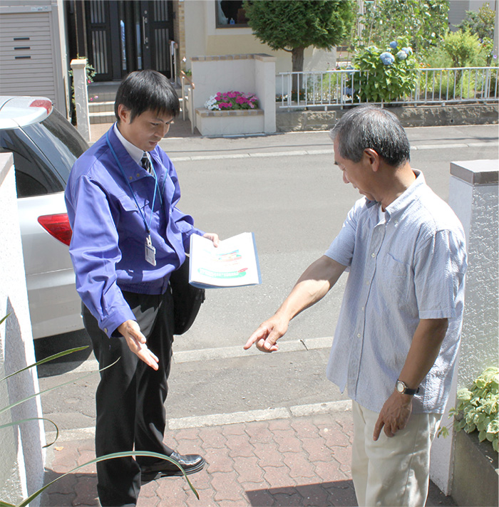 自宅前で男性スタッフに説明している男性客