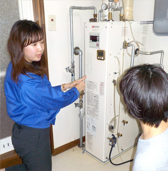 給湯機の説明をする女性スタッフと女性客