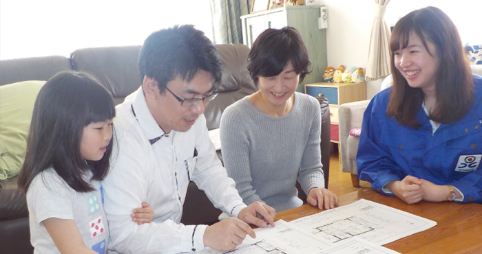 設計図の説明をする女性スタッフと3人家族